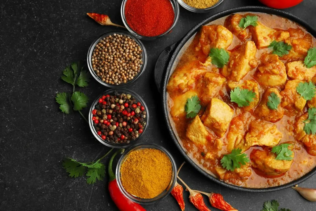 A vegetarian curry surrounded by whole and ground spices