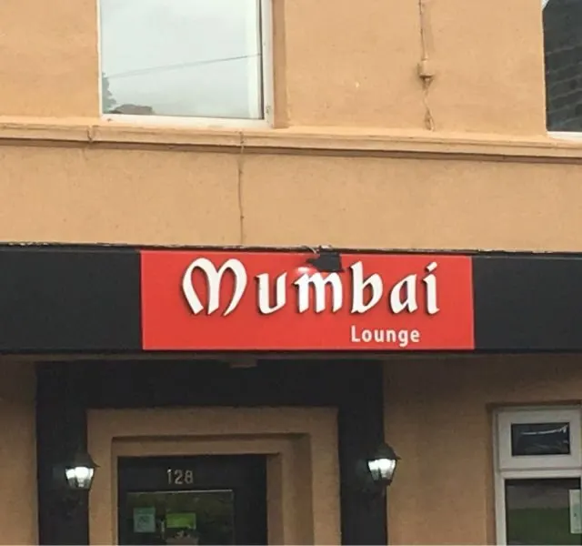 The illuminated Mumbai Lounge sign at night