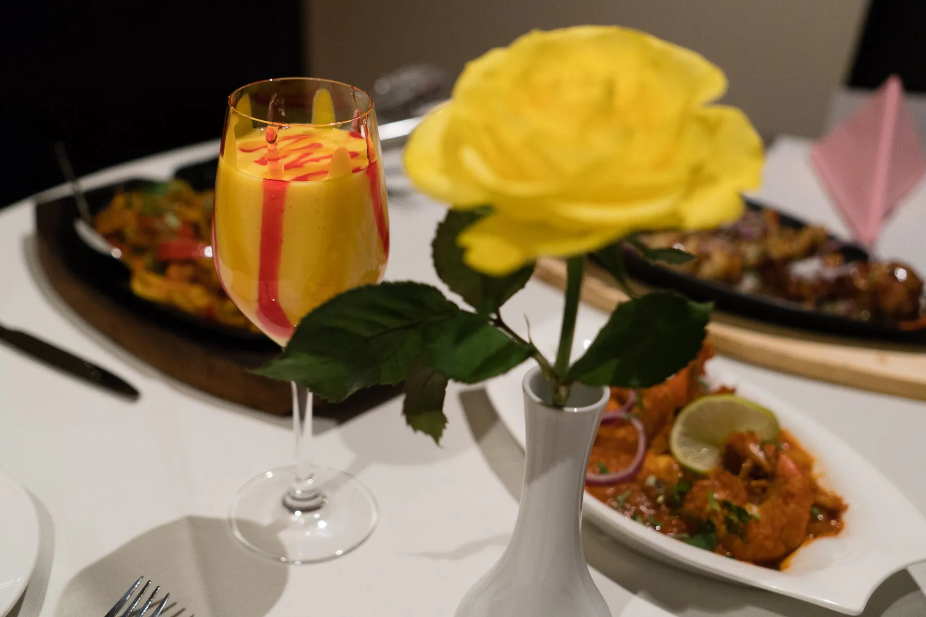 A sizzling tandoori platter served at the table with a drink and a rose